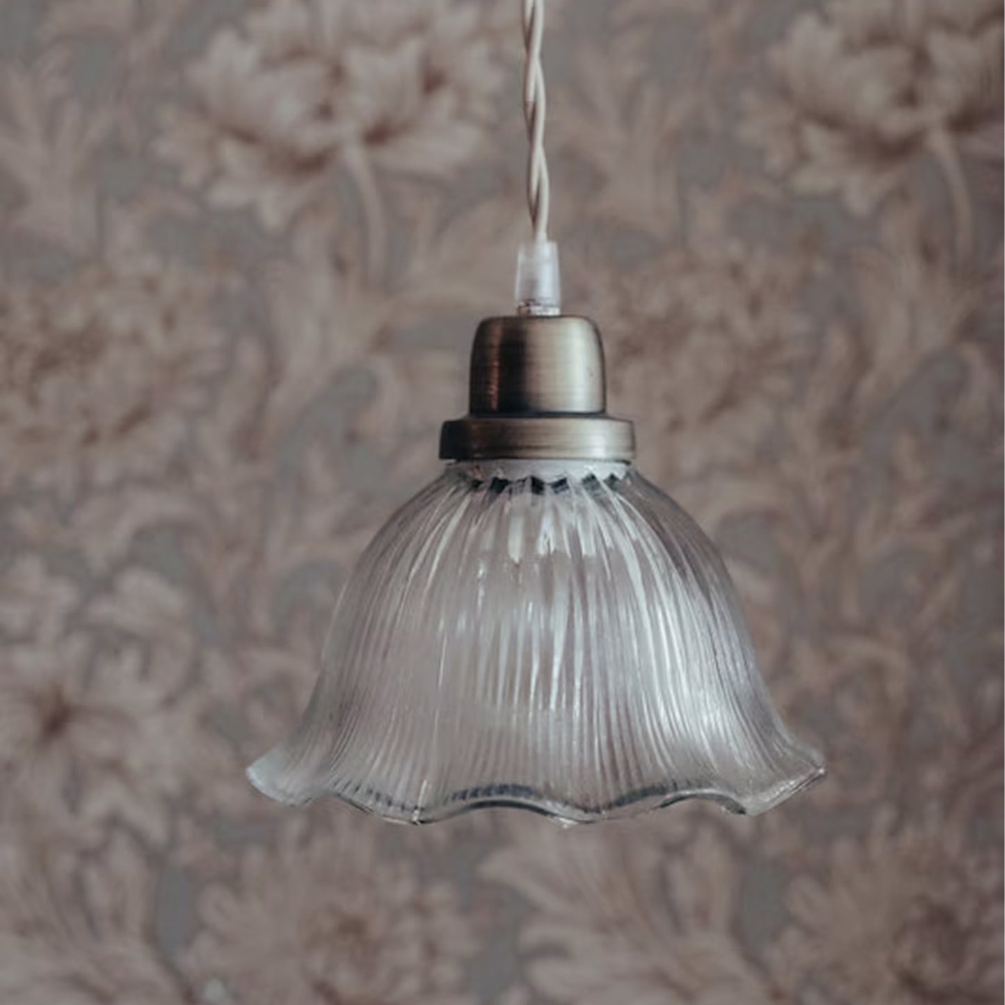 Rocio pendant lamp with wavy clear glass shade and antique brass fixture